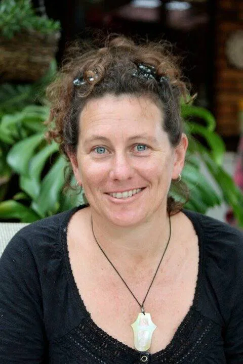 Portrait of Eleanor Davies, smiling with hair tied up and wearing a paua shell necklace.